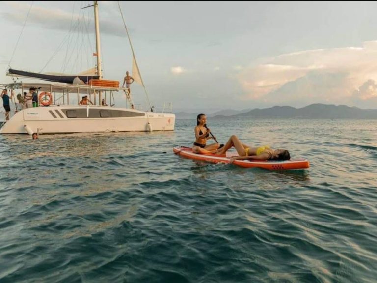 SUP-серфинг в Дананге — девушка на доске для сапборда катается по морской глади возле катамарана